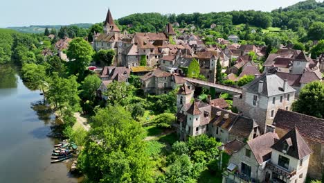 Small,-medieval-village-situated-next-to-a-river,-flowing-through-a-rich-forest-in-the-heart-of-France