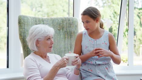 Granddaughter-Sitting-And-Talking-With-Grandmother-During-Visit-To-Retirement-Home