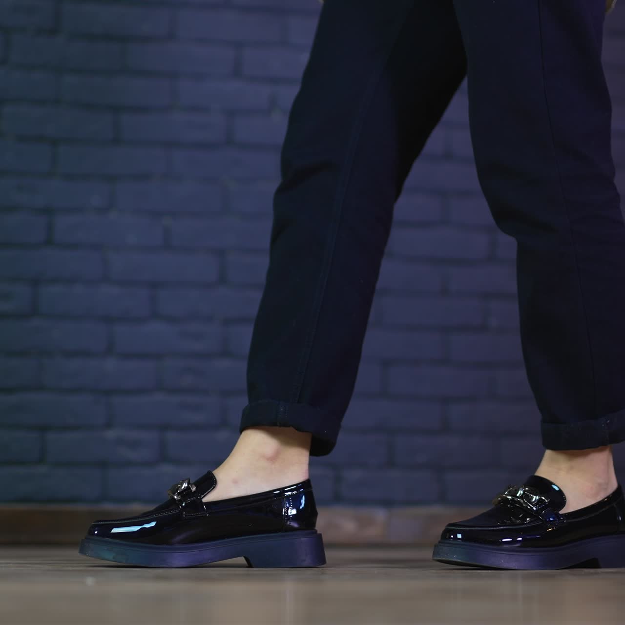Black lacquered shoes with silver chain on massive soles demonstration. Female model rises on toes wearing fashionable shoes