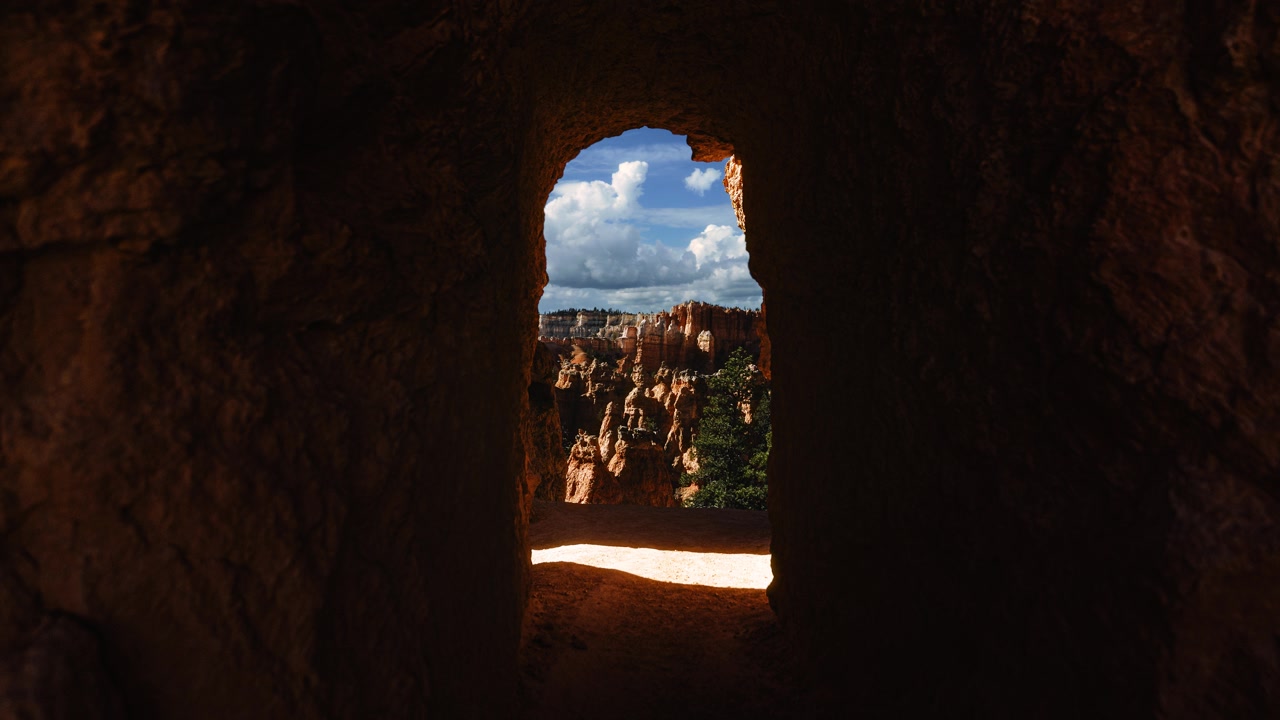Framed view looking through red rock tunnel opening at Bryce Canyon landscape time lapse. Utah, USA.