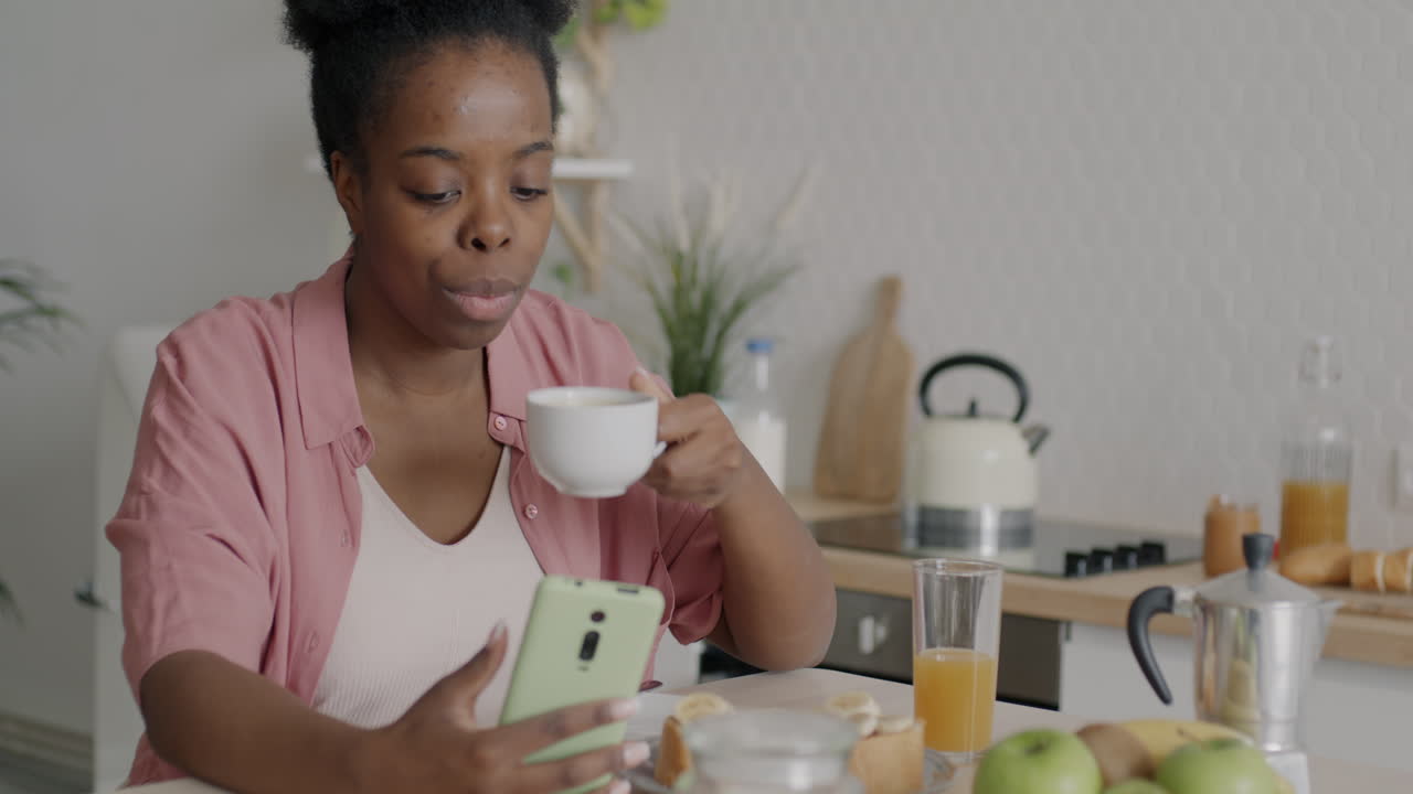 Woman having breakfast while using her mobile phone
