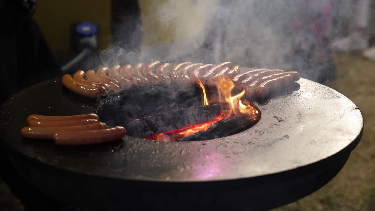 primer plano de salchichas cocinadas en una parrilla caliente con vapor subiendo
