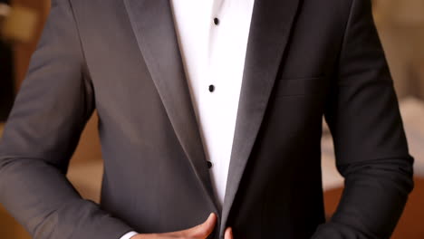 a groom fastens his suit vest and prepares for the wedding - close up