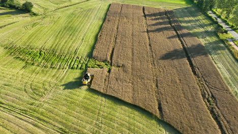 Aerial-view-of-a-combine-harvester-working-in-a-large-brown-field-with-green-surroundings