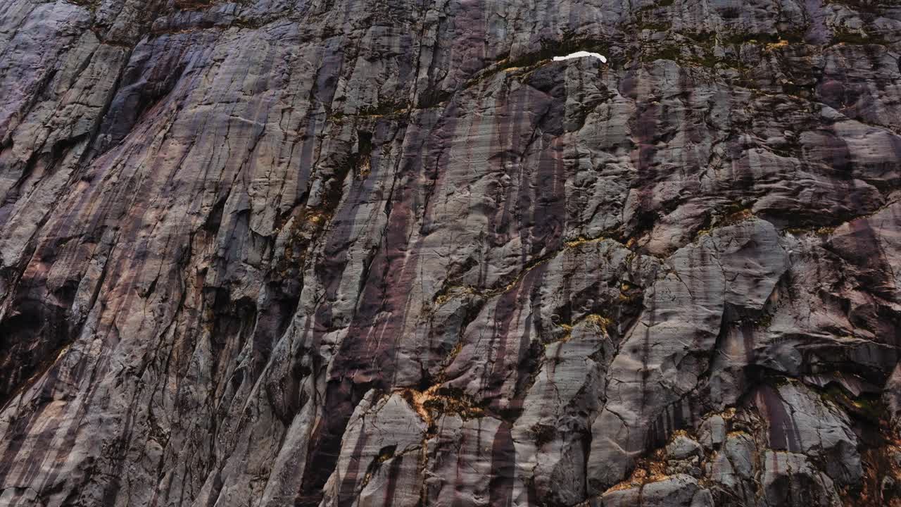 Droneoptagelse af en dramatisk klippeskrænt på Lofoten, teksturerede stenlag og barskt arktisk landskab, vild nordisk natur og geologikoncept.
