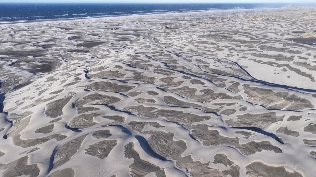 Vista aérea de drone de texturas de areia abstratas e formações de água da maré na Nova Zelândia.