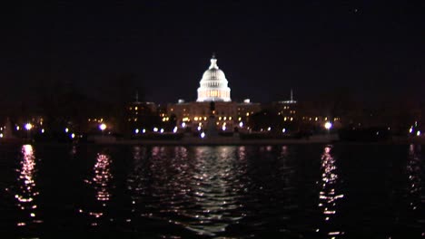 the capitol dome is illuminated as a reflecting pool shimmers below