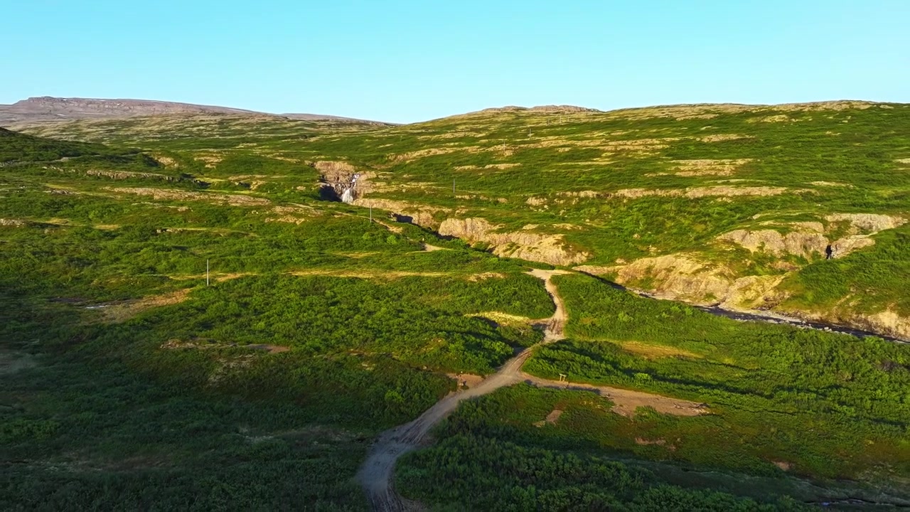 Hyperlapse aereo si allontana sopra le verdi colline e il torrente roccioso dei Fiordi Occidentali