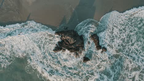 aerial drone top view of rocks in the sea, zooming out revealing the beach in costa rica