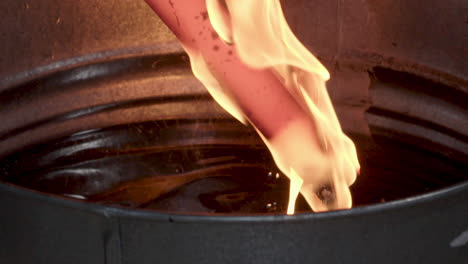 blacksmith pulling burning blade from hot oil