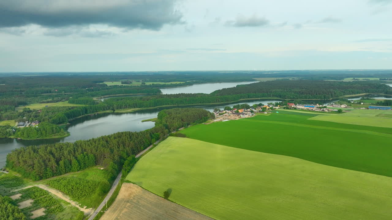 Widok z lotu ptaka na wiejski krajobraz z bujnymi zielonymi polami, meandrującą rzeką i małą wioską.
