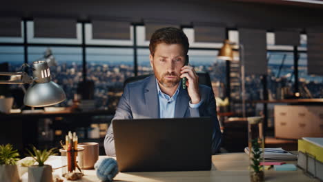 confident boss calling phone evening view office closeup. man talking smartphone
