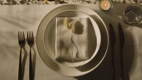 overhead of table setting with plate napkin cutlery and person drinking glass of champagne