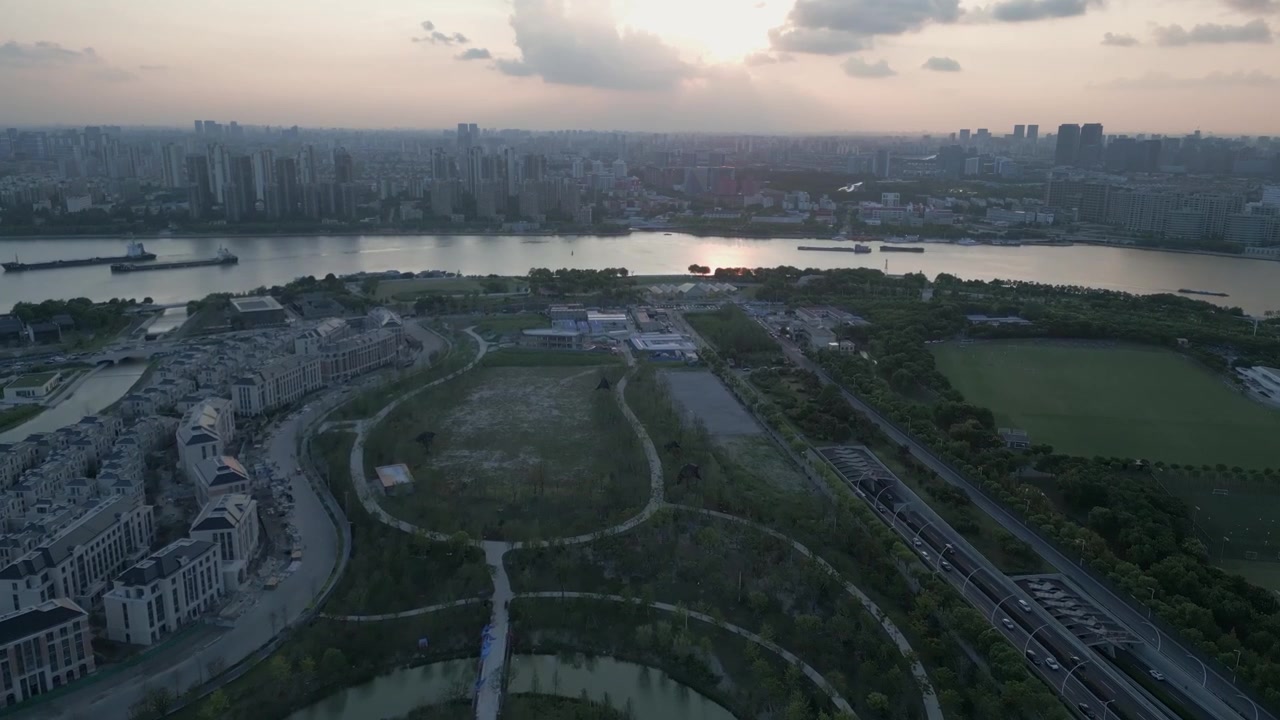 Zachód słońca z drona nad Szanghajem, Chiny. Widok na plac budowy parku Green City, ruch uliczny, rzekę, panoramę miasta i ogromną azjatycką drogę podziemną.