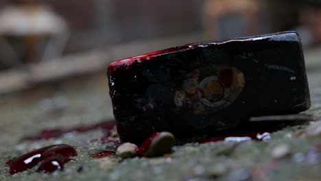 close up of a bloody lump hammer as a light swings overhead and casts shadows onto the grimy concrete floor