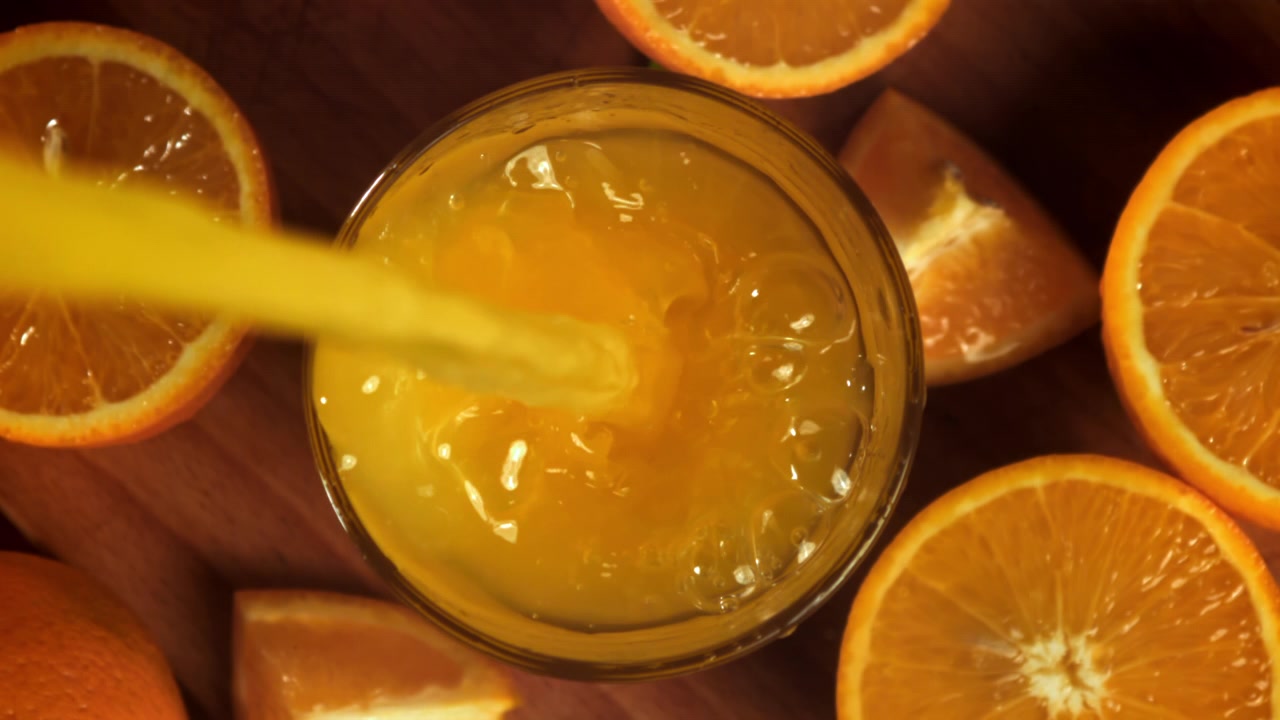 Frisk appelsinjuice hældt i et glas med citrusskiver.