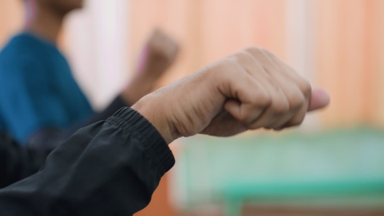 Close up of athletes performing wrist stretching during indoor training session focusing on flexibility, muscle strength, and preparation for sports performance with blurred background