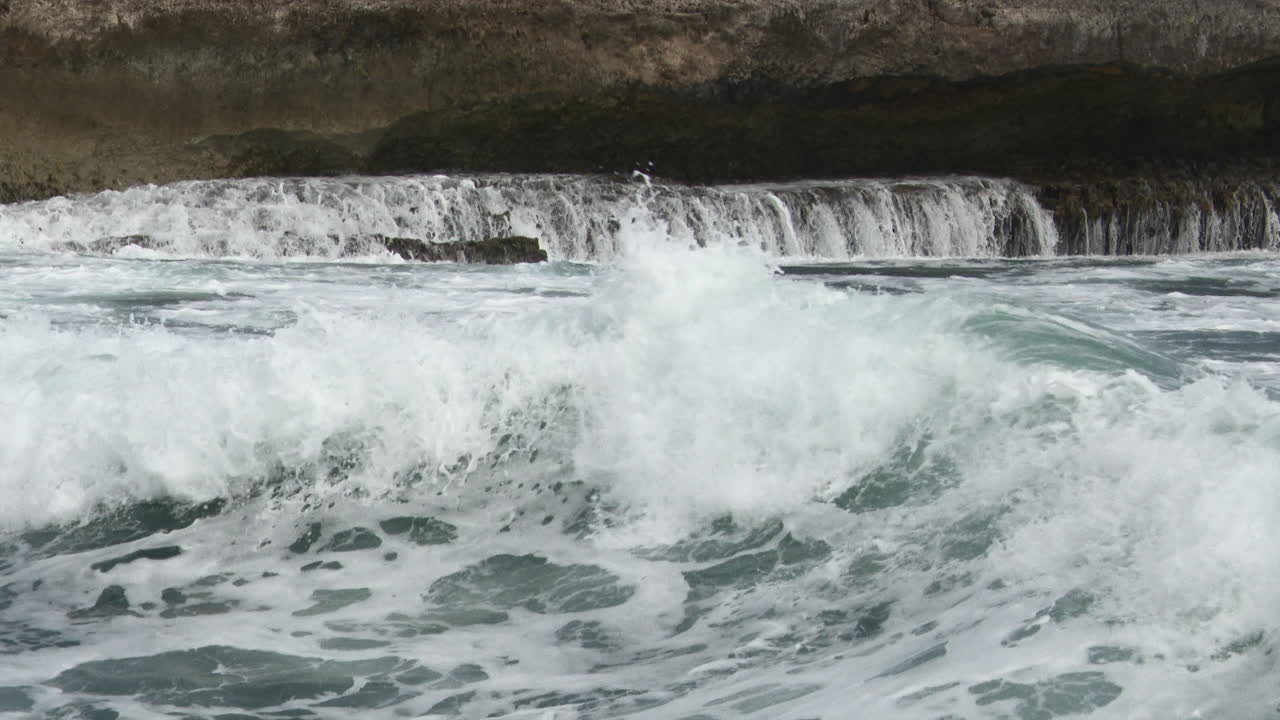 Waves breaking on rocks, creating waterfalls, Close-up, Bonaire
