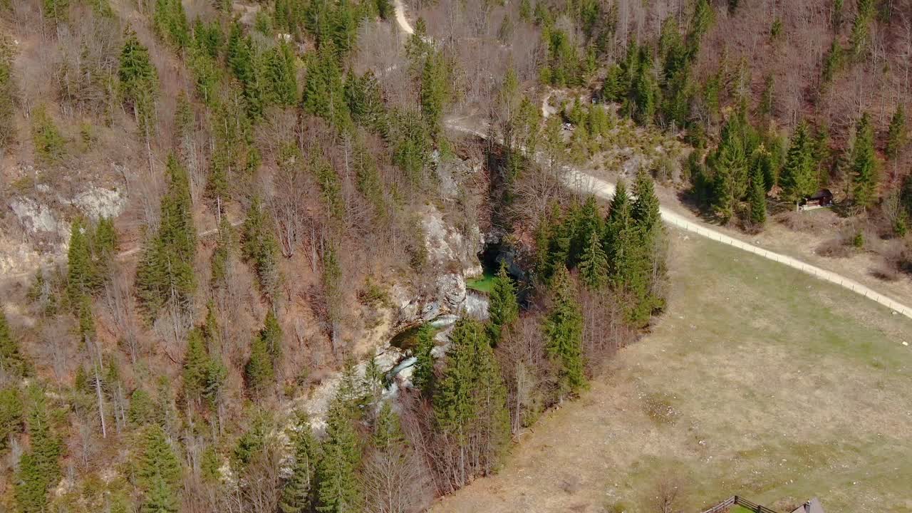 Aerial Over Small Waterfall With Footpath Overhead Surrounded By Trees Near Bohinj. Follow Shot