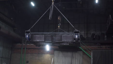 industrial crane lifting a metal platform in a factory