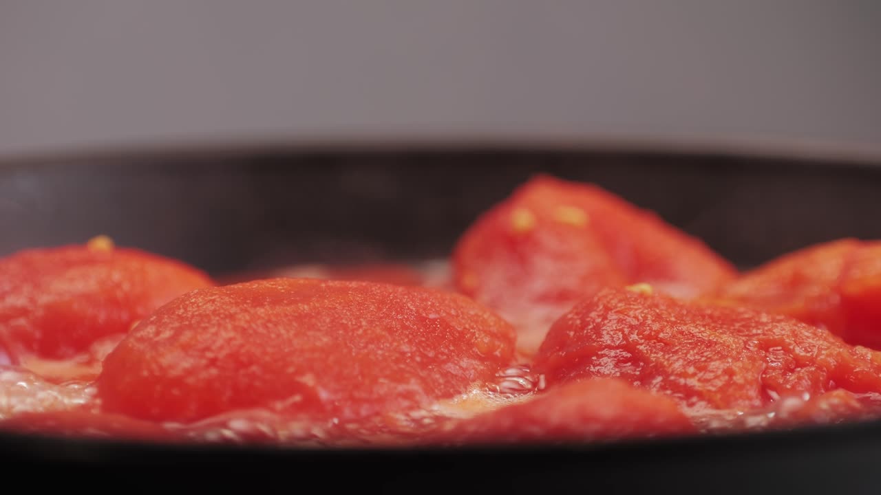 Cooking fresh peeled canned tomato Juice sauce in pan, peeled tomatoes boiling in their own juice, making tomatoes pasta sauce .Top view close up, Italian traditional cuisine food.