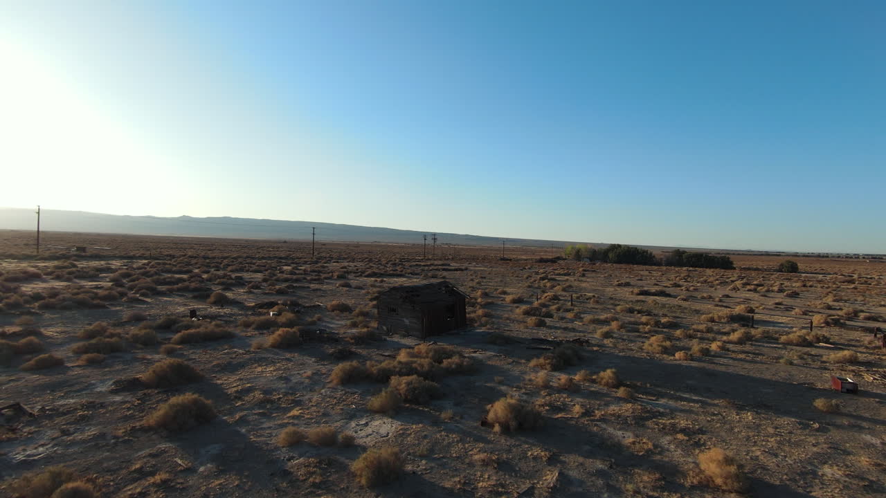volando alrededor de una cabaña abandonada en la pradera del paisaje del desierto de mojave al atardecer
