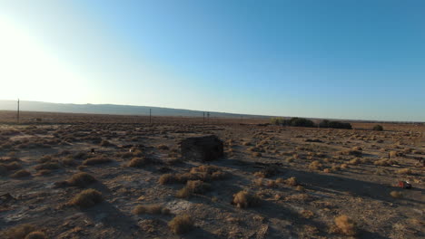 flying around an abandoned cabin in the prairie of the mojave desert landscape at sunset