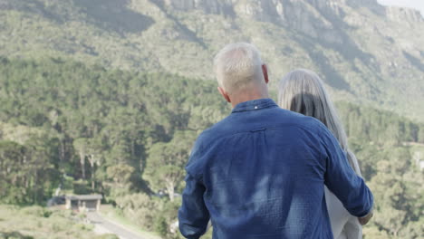 Feliz-Pareja-Caucásica-De-Mediana-Edad-Abrazándose-Y-Hablando-En-Una-Terraza-En-Las-Montañas,-Cámara-Lenta