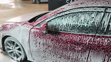 red car being washed with foam