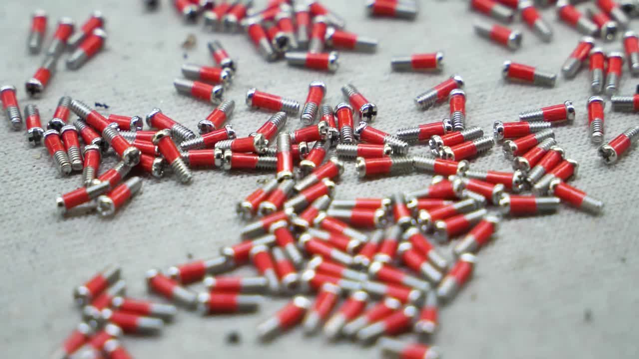Slow-motion close-up view of miniature screws in a spectacle factory. Danyang, Jiangsu Province, China.