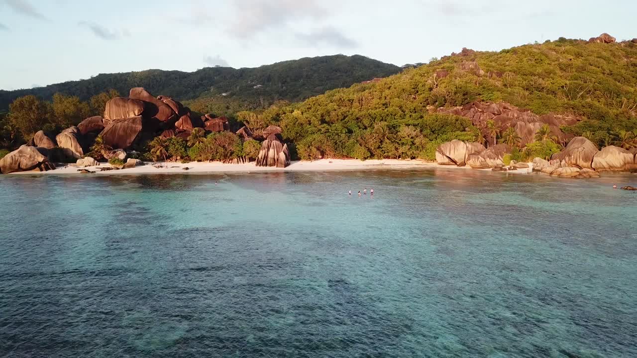 Aerial view of the famous beach on Seychelles, La Digue island. Rising drone shot and people swimming in the lagoon