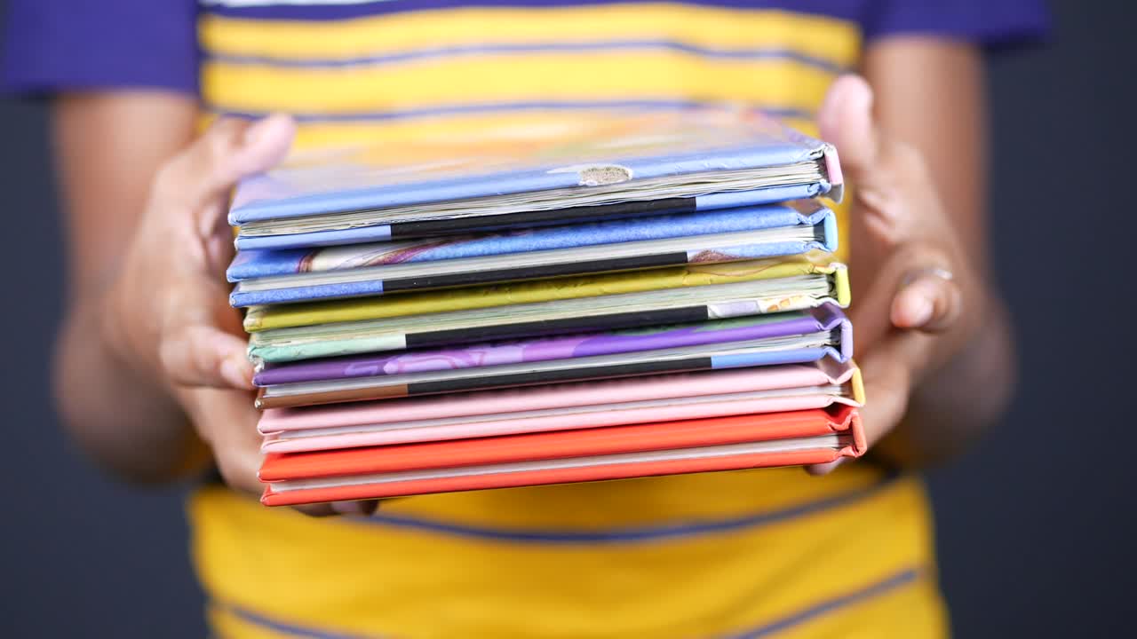 Hands holding a stack of children's books