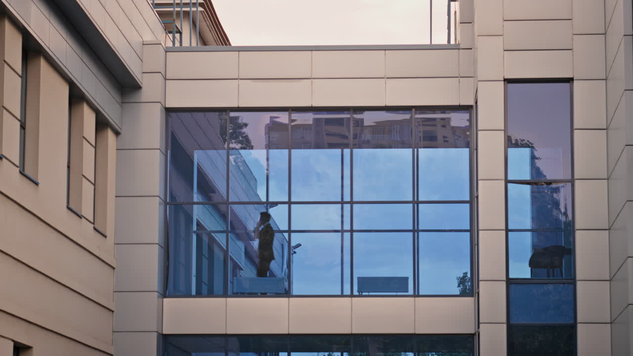 Silhouette businessman crossing modern building talking smartphone. Unknown man