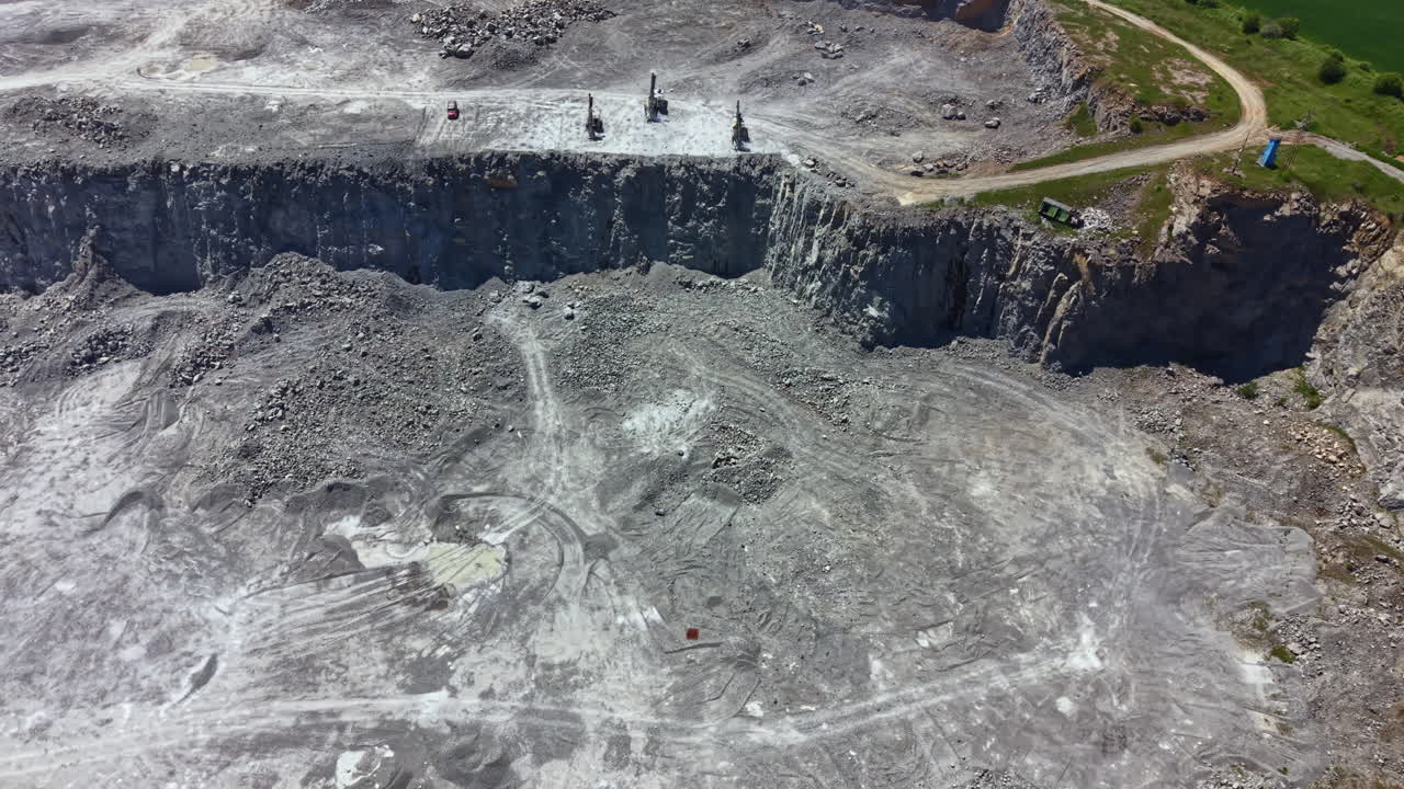 Workers are engaged in stone cutting activities in a quarry located near a river during daylight hours