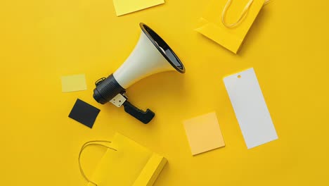 megaphone and shopping bags on yellow background - marketing and sales concept