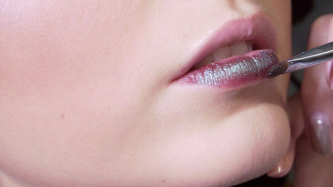 A stylist doing makeup beautiful woman in studio with wavy hairstyle