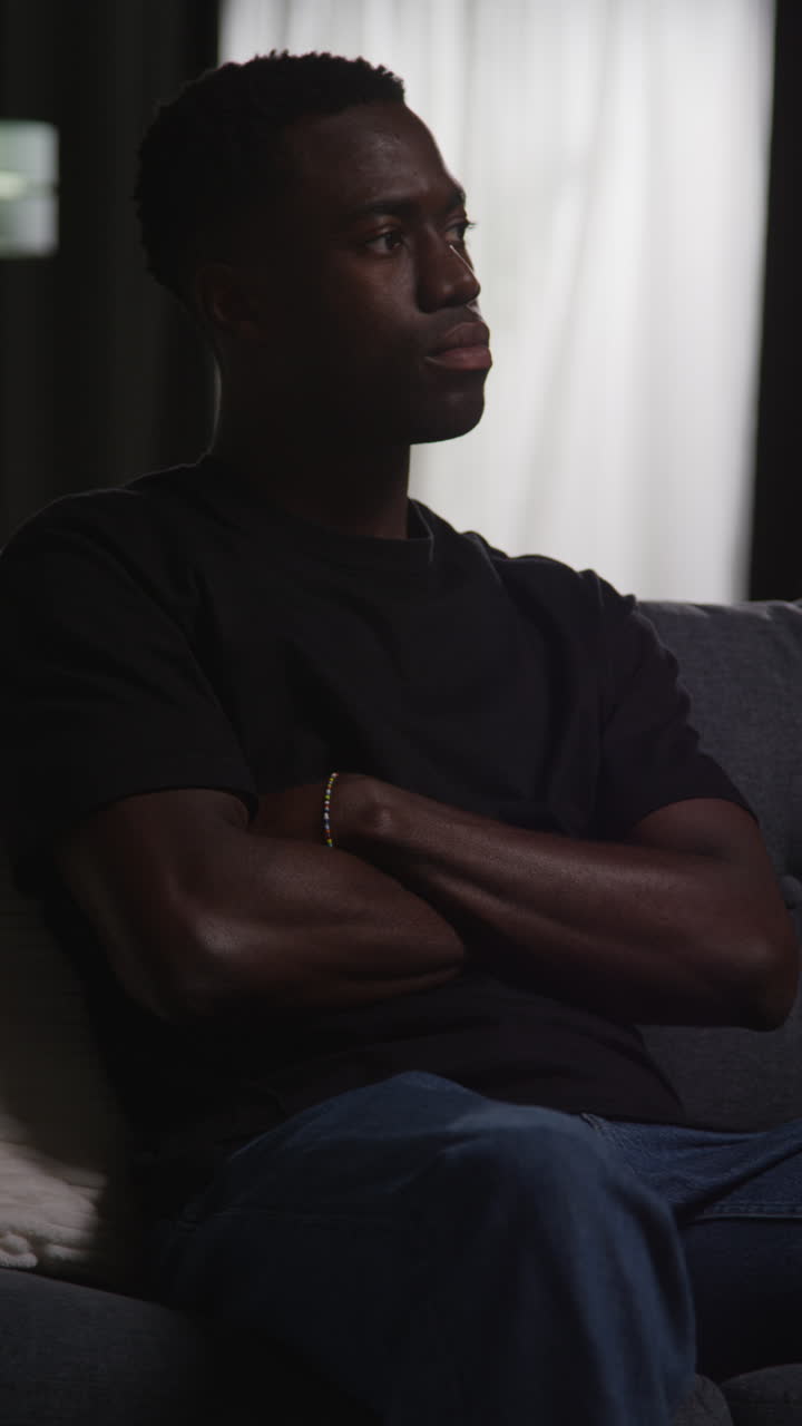 Vertical Video Of Unhappy And Depressed Young Man Sitting On Sofa At Home Looking Anxious And Worried Resting Head On Hand 3
