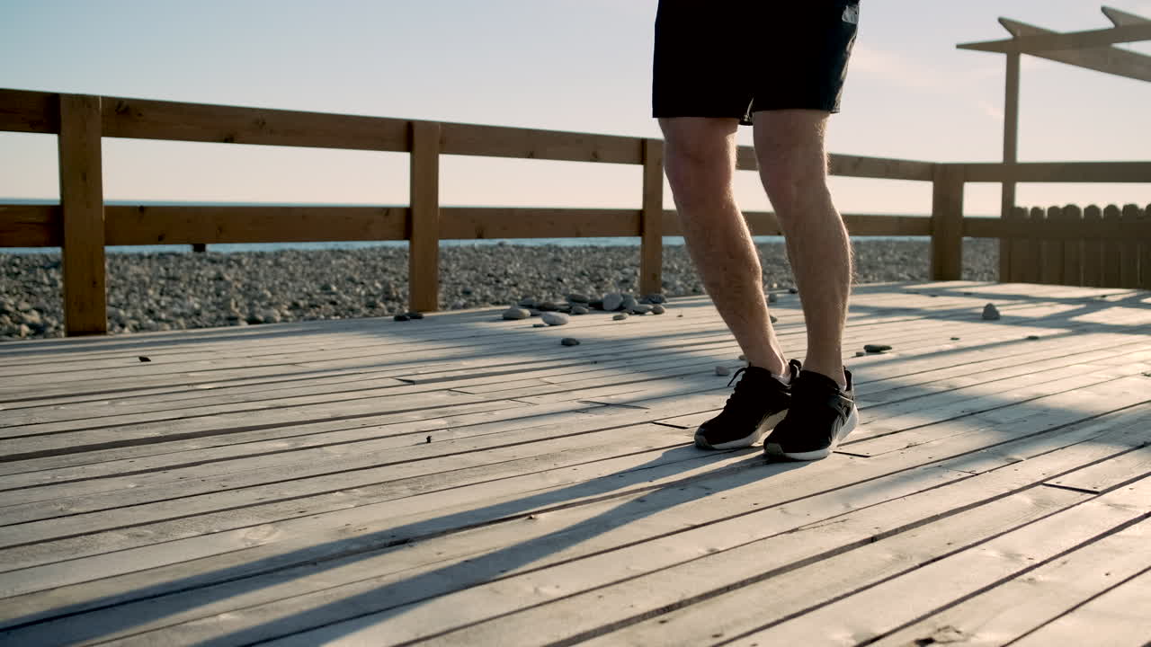 나무로 만든 해변 갑판에서 로프를 뛰어넘는 남자