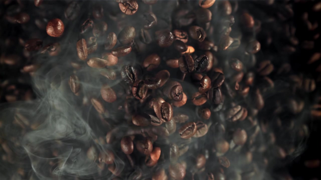 Rallentatore di chicchi di caffè tostati che cadono attraverso il fumo
