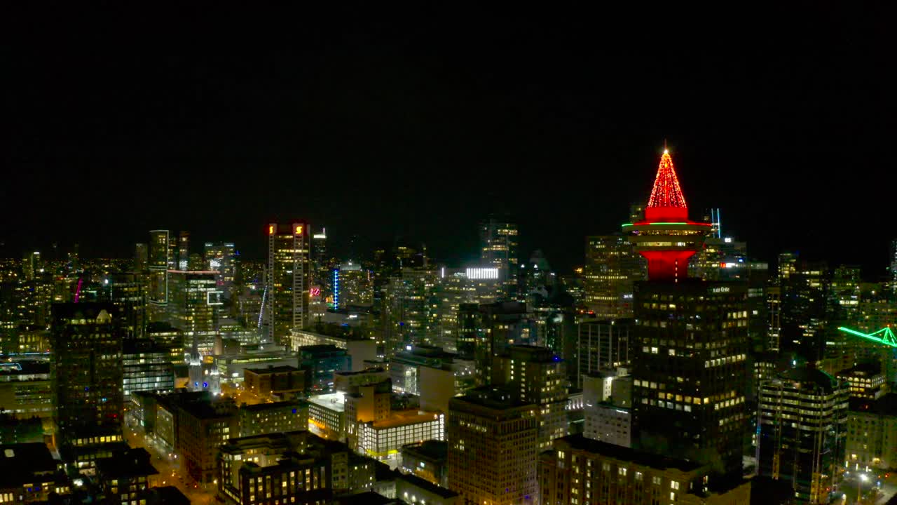 Volo di drone sopra il centro di Vancouver, Canada, di notte, attraverso il Vancouver Lookout.