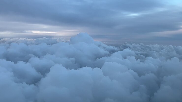 Pilot POV flying over some stormy clouds with a pastel color sky just before sunset