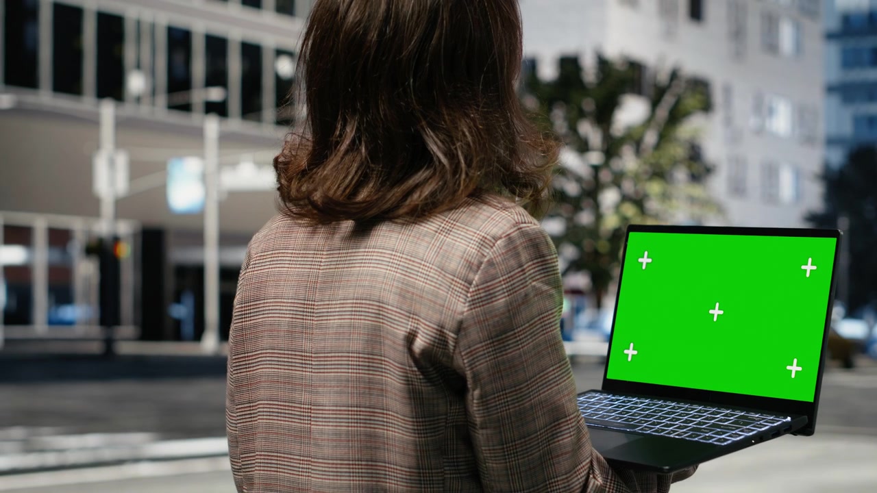 Laptop con schermo in evidenza tenuto da una donna d'affari su un viale cittadino