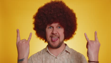 man with an afro wig making funny rock and roll gestures