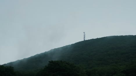 an antenna is seen on top of a mountain during a cloudy day