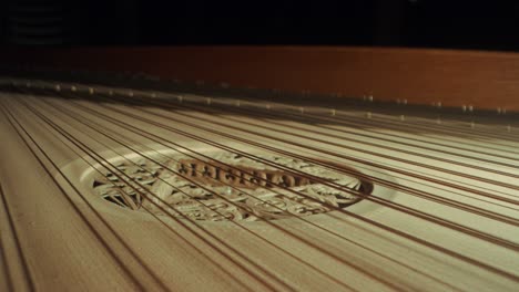 grand piano strings, slight camera movement to the right, closeup, dark, yellow wood