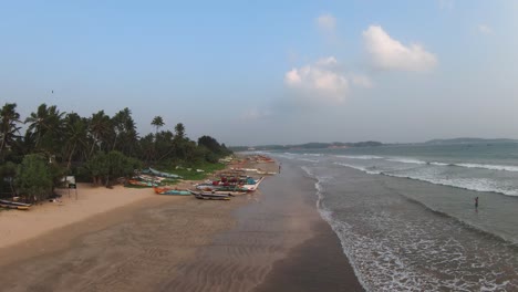 Aerial-Drone-Above-Traditional-Fishing-Boats-And-Tourist-Beach-Scene-In-Mirissa,-Sri-Lanka-On-Sunny-Day