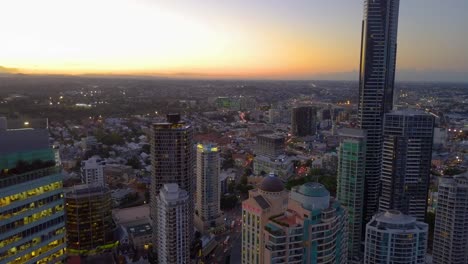 backward moving aerial view of tall buildings at sunset