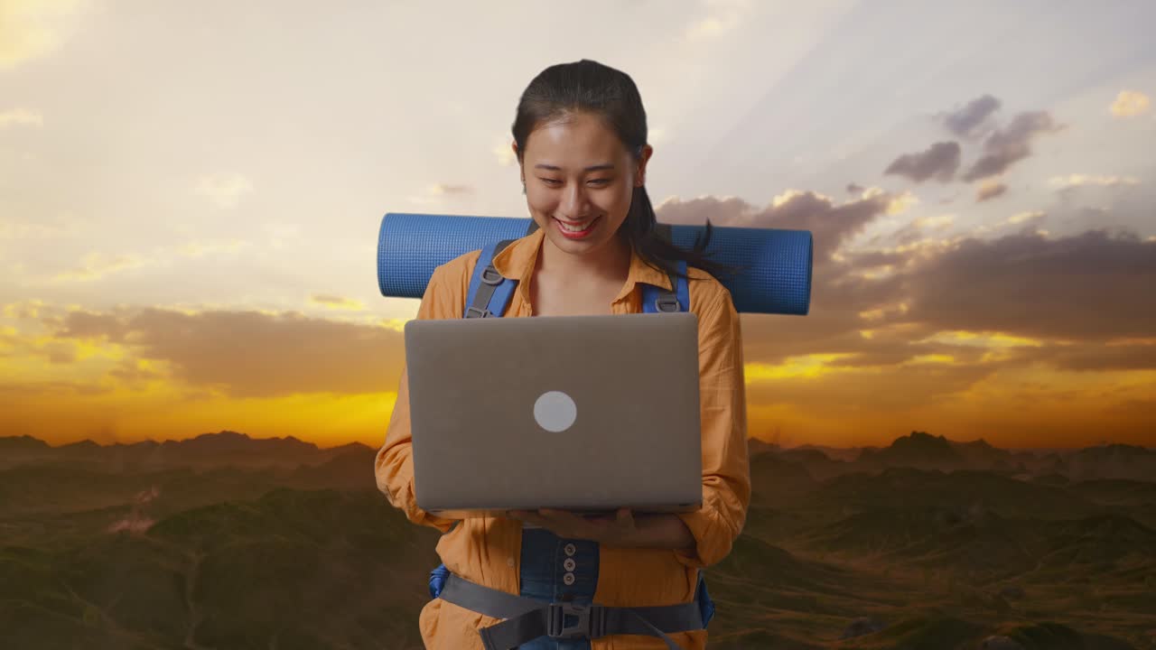 mujer trabajando en una computadora portátil mientras viaja en mochila en las montañas al atardecer
