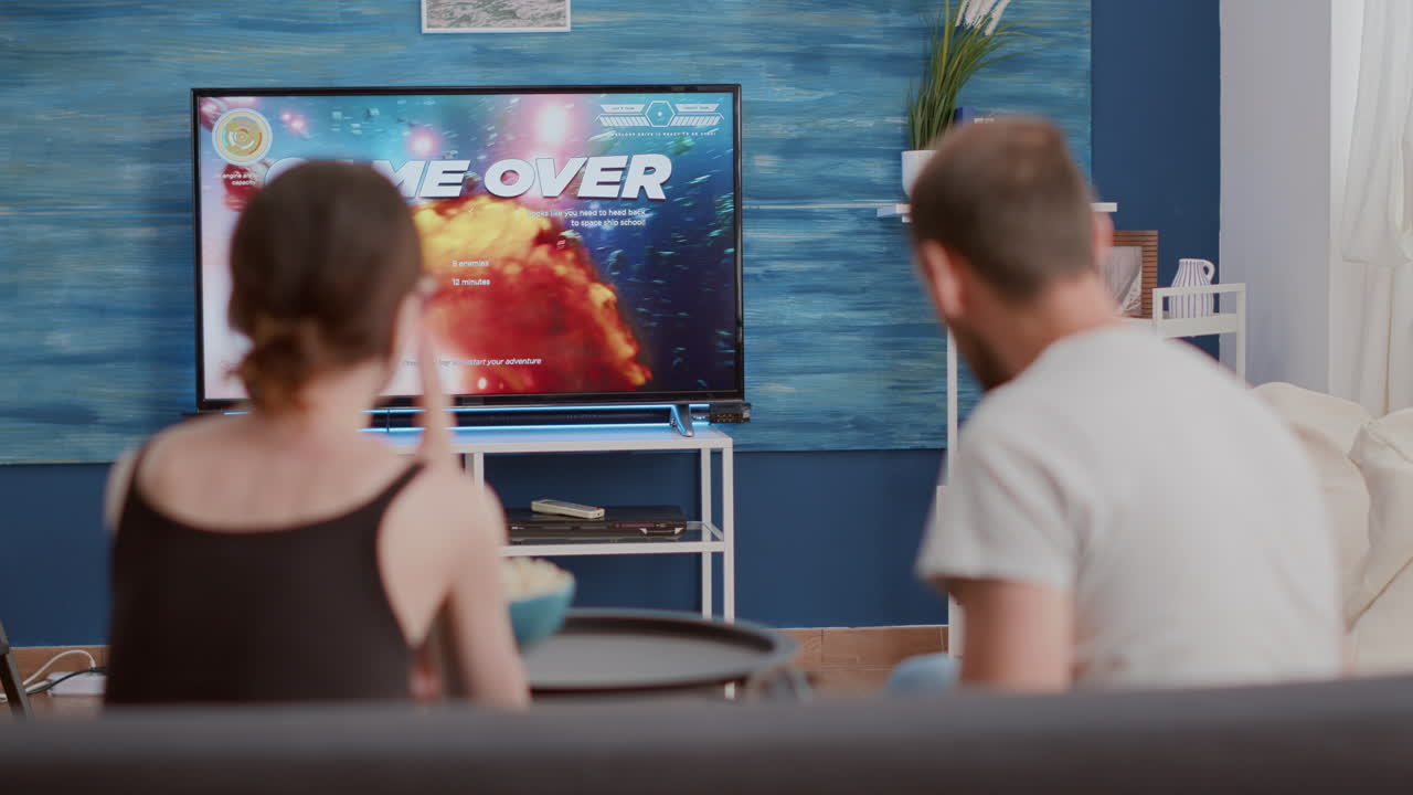 Young woman disappointed because of gamer boyfriend losing online game while playing on console