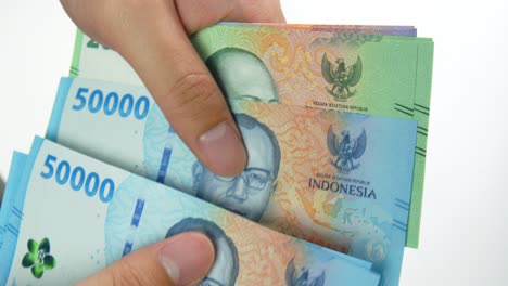 close up of hand counting small amount of indonesian rupiah, small salaryconcept